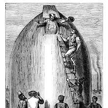 A man appears through an opening at the top of a cannon shell-shaped rocket, greeted by his friends