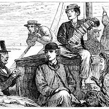 A man plays the concertina for a small group sitting at the rear of a boat