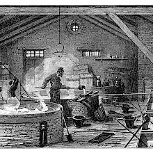 Interior view of a tallow soap factory where workers are attending to the heating soap