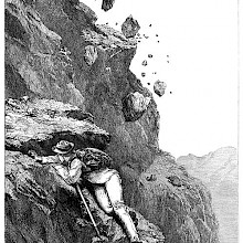 A mountaineer climbing an uneven rock face shelters himself from falling rocks