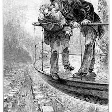 Two men standing on the deck of an aircraft lean over the railing to look at the city below them