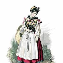 An Alsatian girl in traditional dress stands looking down at a cross on the side of the path