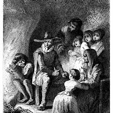 A group of people are gathered around a table near a fireplace