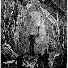 a man holds a torch at the entrance of a tunnel as others stand behind him