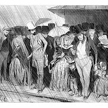 A crowd of travelers is standing on a railway platform, enduring a long wait under the rain