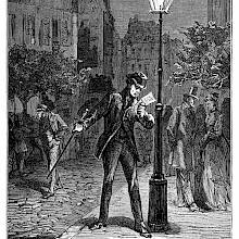 A man has stopped under a streetlight to read a letter as passersby stroll around