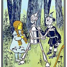 A girl stands in the woods with a robot-like creature and a scarecrow looking like a rag doll