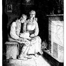 A man is sitting in front of a fireplace, reading from a book as his wife sits on a chair beside him