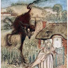 A smiling woman stands at the gate of her house as a large, strange, furry animal suddenly appears behind her