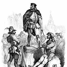 A man wearing a crown-shaped headgear stands on an upside-down half-barrel, holding a whip in one hand