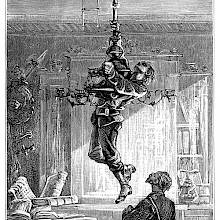 A man hangs on to a chandelier, thus pulling it down and uncovering an opening in the ceiling