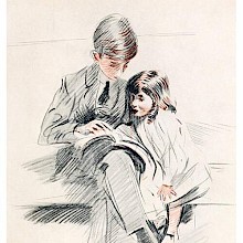 A boy is sitting on a couch with his younger sister and shows her something from a book