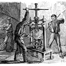 View of a workshop where two men are busy around a mobile press for molding goblets