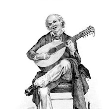 A smiling middle-aged man sits on a chair playing the twelve-string mandolin