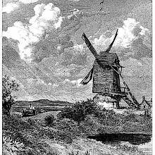 View of a windmill standing in the open countryside with a pond in the foreground