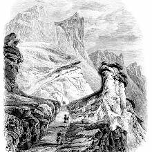 Hikers can be seen on a rocky mountain path, heading to the summit that towers high above them