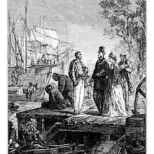 Three people stand discussing on a dock, while lightermen are busy in the foreground