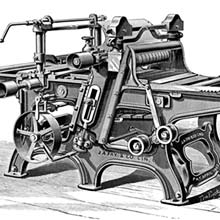 Three-quarter view of a double surfacing planer, with a spoked drive wheel visible on the near side