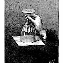 A hand holds a glass upside down as the water inside is kept from running out by a sheet of paper