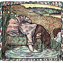A girl lies on a riverbank with her arm in the water to put a fish back in the river