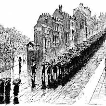 A funeral procession moves up a long and steeply sloping street in the rain
