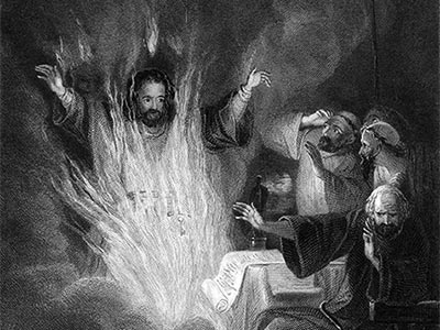 A man performs a ritual in front of bewildered onlookers, resulting in rising flames and smoke
