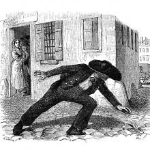 In a cobbled street, a man wearing a hat leans forward to pick up a message
