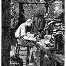 A polisher is sitting at a workbench operating a buff wheel
