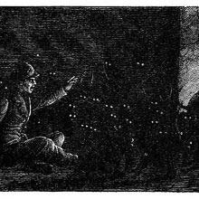 A man sitting in a dark room gestures toward a cat looking into a pot on the fire