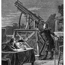 A man standing on a terrace is looking at the sky through a telescope