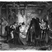 People are gathered round a table in a rustic home late in the evening