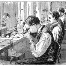 Workshop of a watch factory with men at work sitting on the chairs lining the workbench