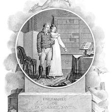 A man and his wife stand together as she gestures toward a table on which a violin can be seen