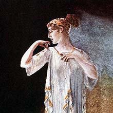 A woman stands against a strongly contrasted background wearing a dress in the Greek style