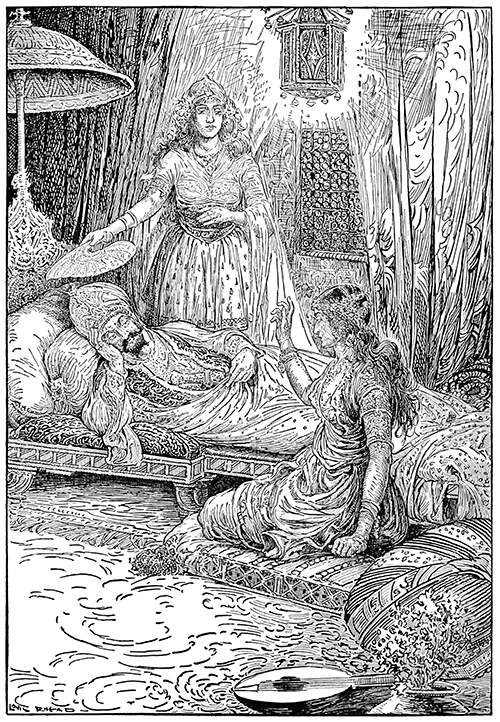 A man is lying on a low couch, listening to a woman sitting on a cushion on the floor