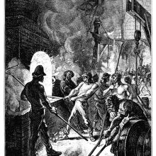 A puddler stands in front of a furnace, maneuvering the hook as a helper stays behind him