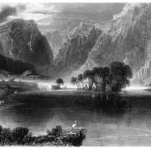 View of Gougane Lake with a clump of trees on an island and mountains in the background