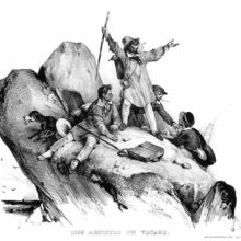 A man throws up his arms in triumph as he reaches a rocky peak, his companions around him