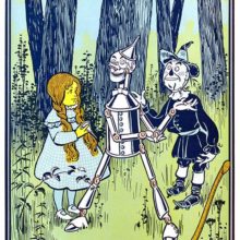 A girl stands in the woods with a robot-like creature and a scarecrow looking like a rag doll