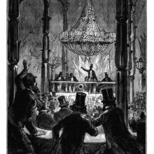 view of a conference hall showing a cheering audience seen from behind and a speaker on a platform