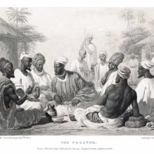 A group of men is sitting in a circle, having a discussion while onlookers stand at some distance
