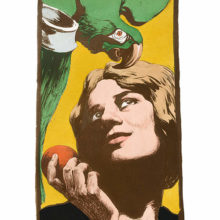 A woman is gazing up to the green parrot she's tempting with a fruit she holds in her hand