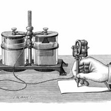 A hand is seen writing on a stencil with Edison's electric pen connected to a wet cell battery