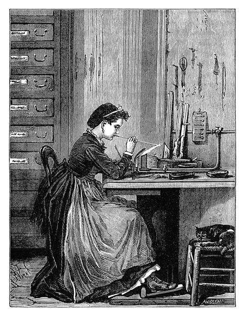 A woman sitting at a work table is blowing a glass imitation pearl by the flame of a gas burner