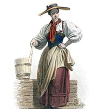 A Swiss girl in the traditional costume of Brienz stands looking down with one hand on her hip