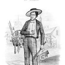 A dry-goods dealer stands in the middle of a street with a basket full of notions items on his arm