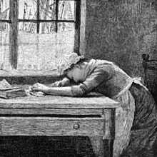 A grieving woman is seen from the side, leaning over a wooden table with her forehead resting on her right arm